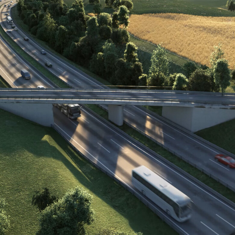Bridge over motorway between trees, meadows and fields on sunny day with cars, bus and trucks driving fast.